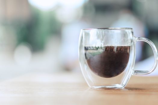 Closeup glass of hot americano coffee on wood table, selective focus, vintage tone