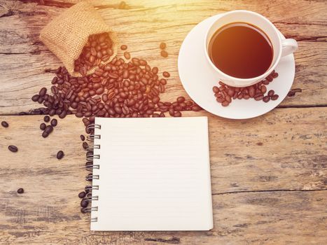 hot coffee cup with coffee bean and notebook on wooden table. coffee background menu for cafe or coffee shop