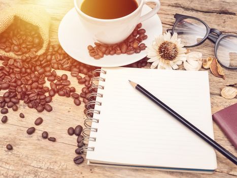 hot coffee cup with coffee bean and notebook with pencil on wooden table. coffee background menu for cafe or coffee shop