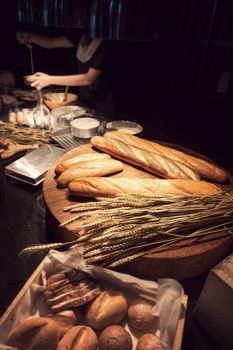 freshly homemade baked traditional bread on wooden table with woman baking bakery at background