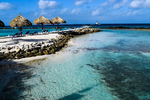 Aruba, Renaissance Island, Caribbean Sea. Sunny beach with white sand, coconut palm trees and turquoise sea. Summer vacation, tropical beach and pink flamingos