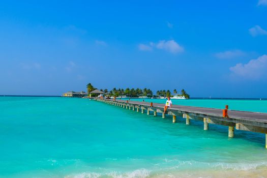 Sunny beach with white sand, coconut palm trees and turquoise sea. Summer vacation and tropical beach concept. Overwater at Maldive Island resort.