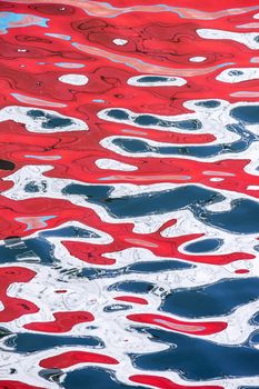 Red and white reflections of a ship on the surface of the sea. Abstract background.