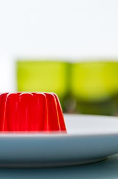 Close-up of a strawberry jelly dessert with a two green glasses in the background