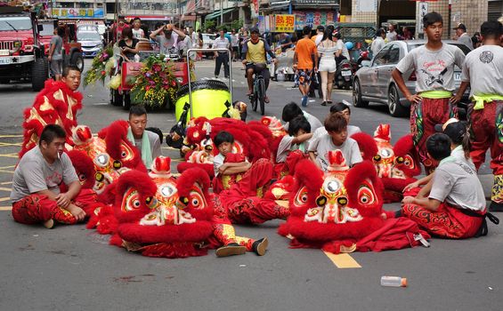 KAOHSIUNG, TAIWAN -- JULY 9, 2016: Male lion dancers are resting between performances during a traditional religious temple ceremony.