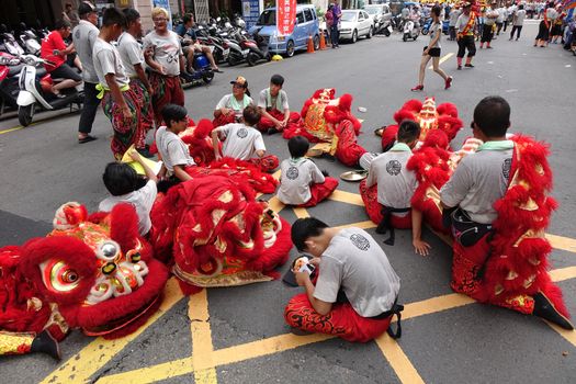 KAOHSIUNG, TAIWAN -- JULY 9, 2016: Male lion dancers are resting between performances during a traditional religious temple ceremony.
