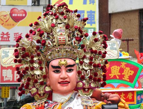KAOHSIUNG, TAIWAN -- JULY 9, 2016: A dancer with a large face mask performs during a traditional religious temple ceremony.