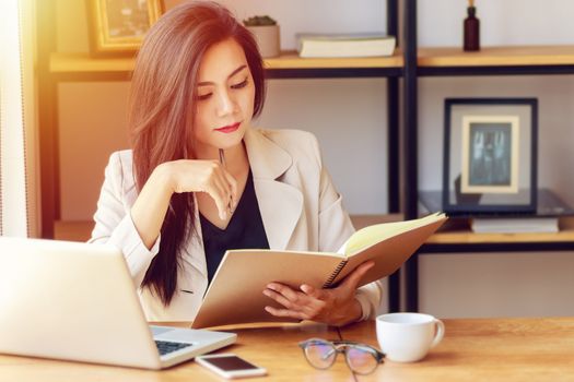 young Asian business woman working at workplace. beautiful Asian woman in casual suit working with reading book, prepare for meeting or interview in modern office. freelance, start up business in Asia