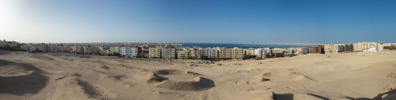 Panorama of large coastal town city with sea view on edge of arid harsh desert landscape