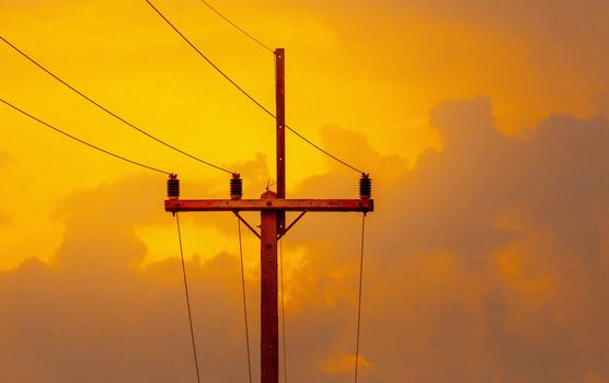 Electric poles with cables of electric on sunset background in evening.