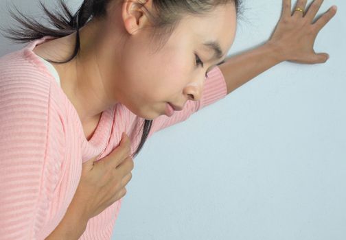 Asian young woman suffering from chest pain caused by heart disease.