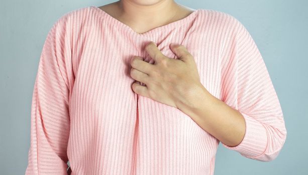 Asian young woman suffering from chest pain caused by heart disease.