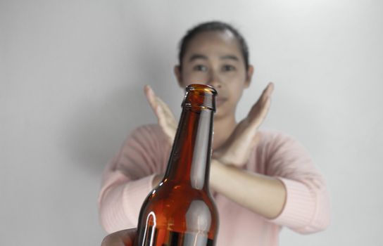 Asian woman refuses alcohol; isolated on grey background. Stop alcoholism