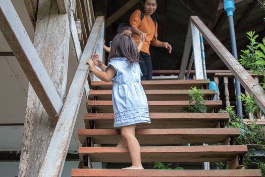 Asian little child girl walking up on wooden stair in restaurant. Dangerous in children.
