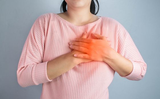 Asian young woman suffering from chest pain caused by heart disease.