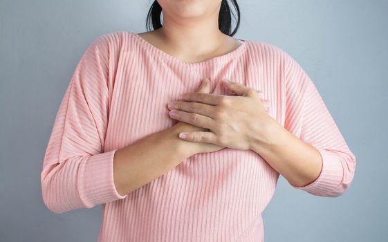 Asian young woman suffering from chest pain caused by heart disease.