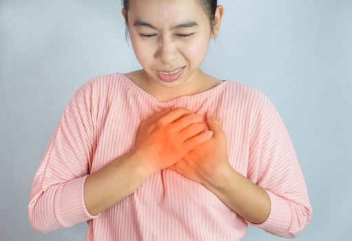 Asian young woman suffering from chest pain caused by heart disease.