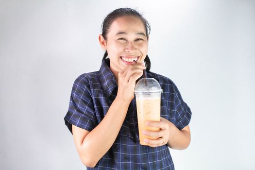 Happy Asian young woman is drinking Thai tea with milk. Popular beverage in Asia.