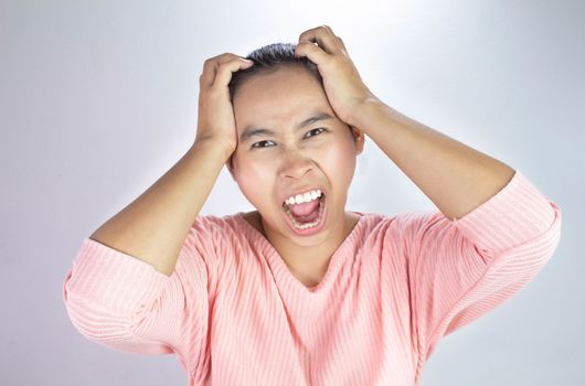 Portrait of a stressed woman holding head in hands and yells loudly angry.