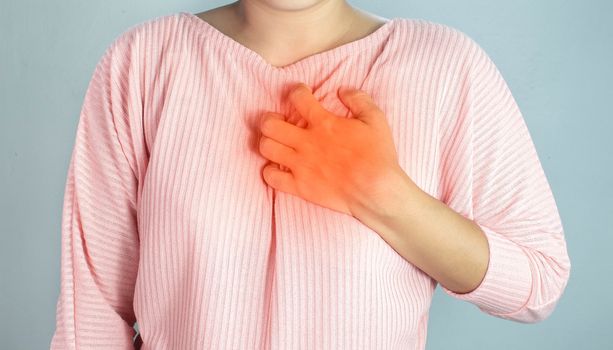 Asian young woman suffering from chest pain caused by heart disease.