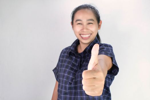 Portrait of Asian young woman in blue shirt, making outstretched hands with thumbs up sign and smiling cheerfully, showing her support. Body language and encouragement concept.