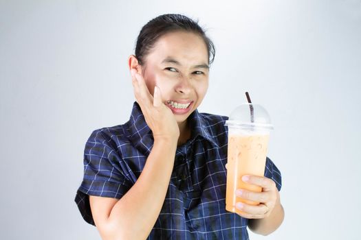 Asian young woman touching cheek with hand because she tooth sensitivity and toothache from drinking cold water. Dental care and health concept.