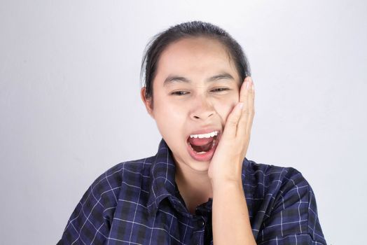 Asian woman touching cheek with hand because she is suffering of toothache. Dental care and health concept.