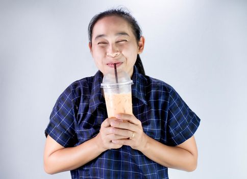 Happy Asian young woman is drinking Thai tea with milk. Popular beverage in Asia.