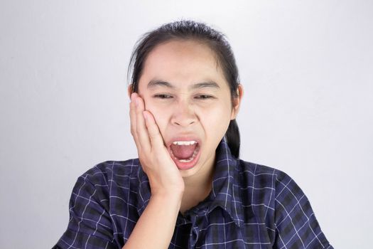 Asian woman touching cheek with hand because she is suffering of toothache. Dental care and health concept.