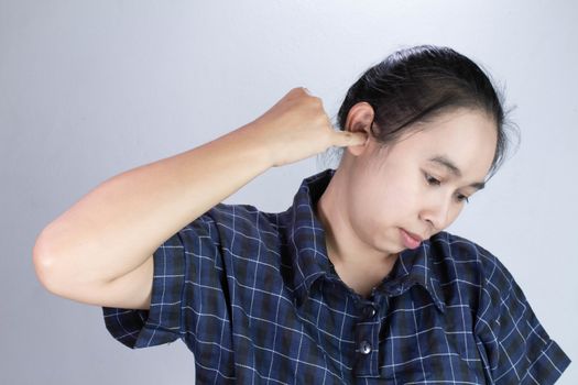 Asian young woman has itchy ear and using finger to scratching ear, isolated on grey background.