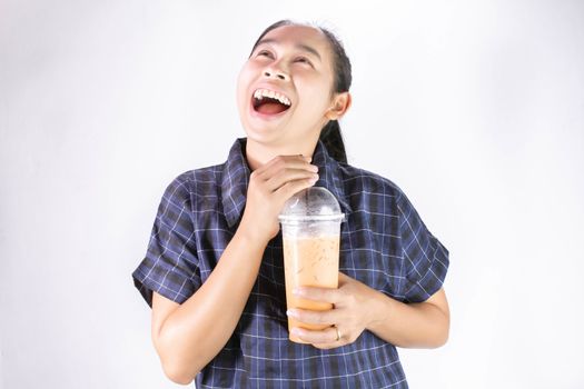 Happy Asian young woman is drinking Thai tea with milk. Popular beverage in Asia.