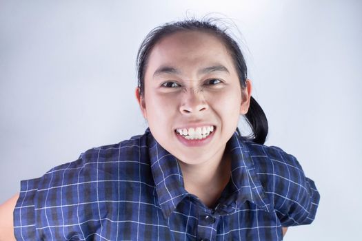 Close-up Angry face of Asian young woman in blue shirt with look to the camera.