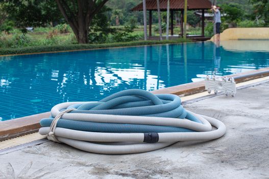 Swimming pool vacuum cleaner hose on cement floor, Manual equipment for cleaning pool.