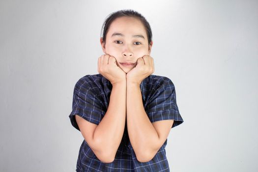 Portrait of young woman looking bored and put hands on chin isolated on a grey background.