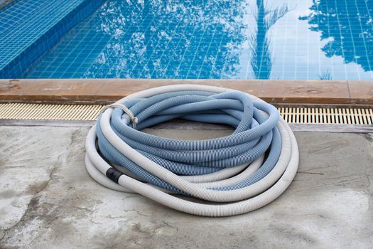 Swimming pool vacuum cleaner hose on cement floor, Manual equipment for cleaning pool.