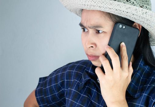 Asian young woman angry while talking on phone in vacation day, Isolated on grey background.