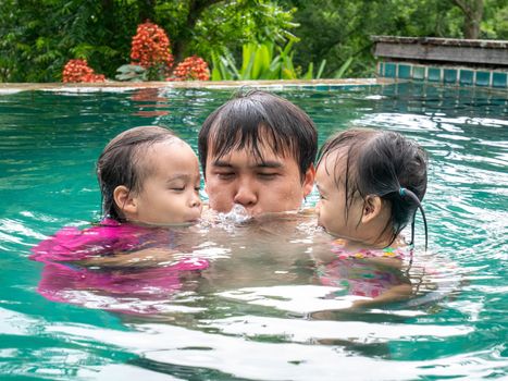 Portrait of Father and daughter enjoying a summer holiday in swimming pool at Northern resort of Thailand.