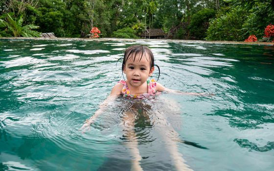 Portrait of little asian child girl enjoying a summer holiday in swimming pool at Northern resort of Thailand.