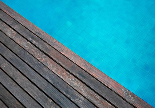 Wooden floor and wave of water in swimming pool in summer day.