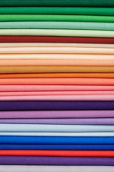 Stack of bright self-colored cotton fabrics as a background image