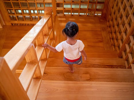 Asian young child girl walking on wooden stairs in Hinoki Land; Japanese building style for travel in Chaiprakarn district Chiang Mai,Thailand.