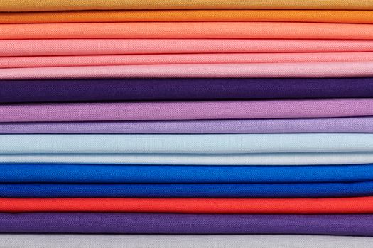 Stack of bright self-colored cotton fabrics as a background image