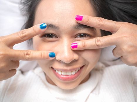 Close-up of female showing hands paint nail varnish with smiley face, self made manicure at home.