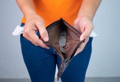 Unemployed and bankrupt woman showing little coin into her wallet. Concept of economic recession.