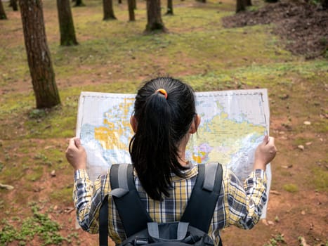 Young woman traveler with map and backpack relaxing outdoor at nature trail on summer vacations day. Lifestyle hiking concept.