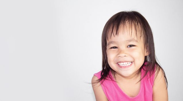 Happy Asian child girl wearing pink dress isolated on white background.