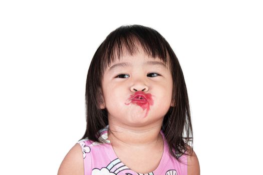 Adorable asian little girl making kiss with mess lipstick all over mouth. learning activity to be a beautiful woman.