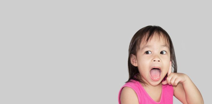 Adorable Asian child thinking isolated on a grey background with space for text.