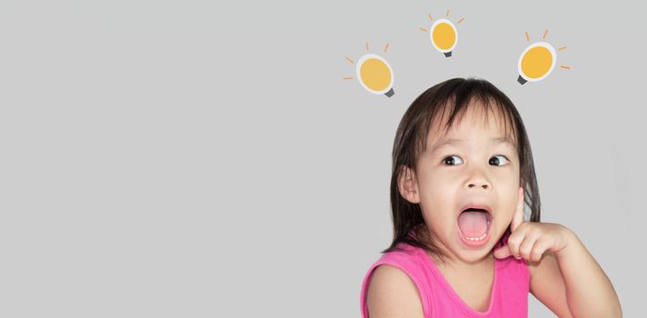 Adorable Asian child thinking and wearing pink dress isolated on a grey background.