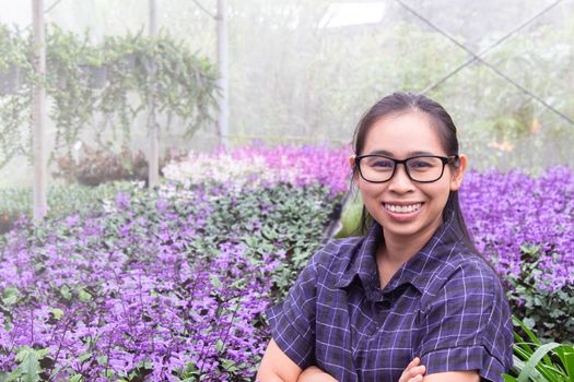 Gardener Asian woman standing and cross one's arm proud in the growing flowers in greenhouse.